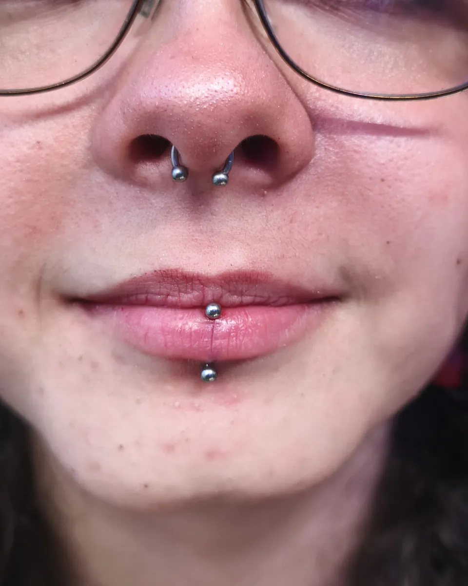 Perforaciones en las dos aletas de la nariz y un labret vertical en el labio