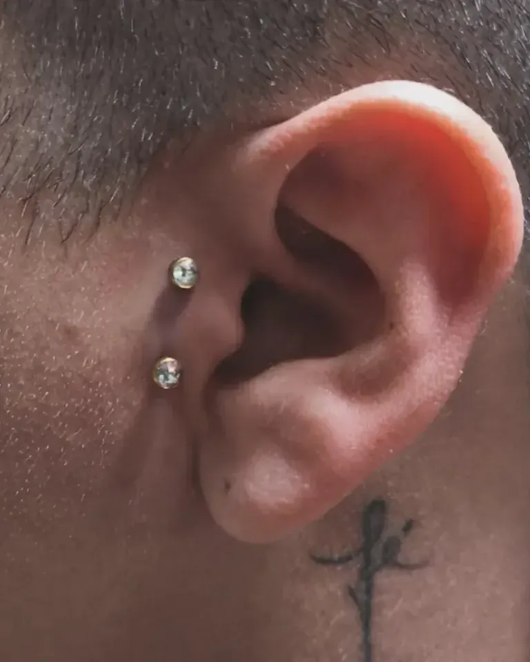 Dos perforaciones con joya de brillante en el cartílago de una oreja