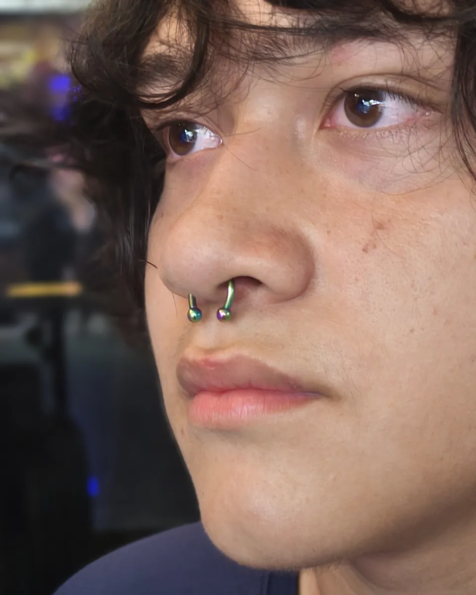 Septum con aro dorado y perforación en la aleta de la nariz